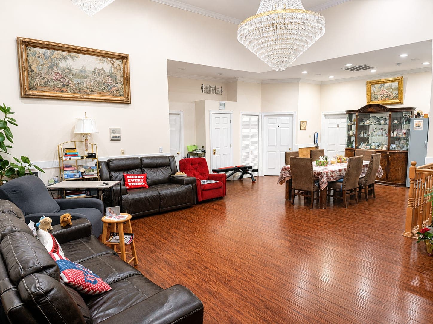 The shared living room — sofas on a wood floor beneath a chandelier, with the dining table beyond.